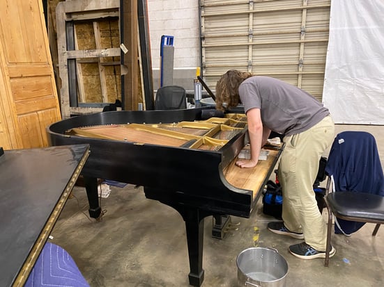 Mumford's piano specialist does some technical work on a piano.
