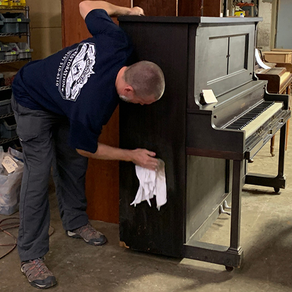 Jason cleans a piano before it goes back to the client.